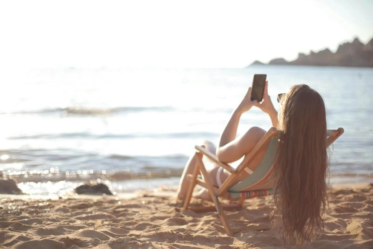 travel quiz Traveler using a laptop by the waterfront to research destinations using AI-powered search tools